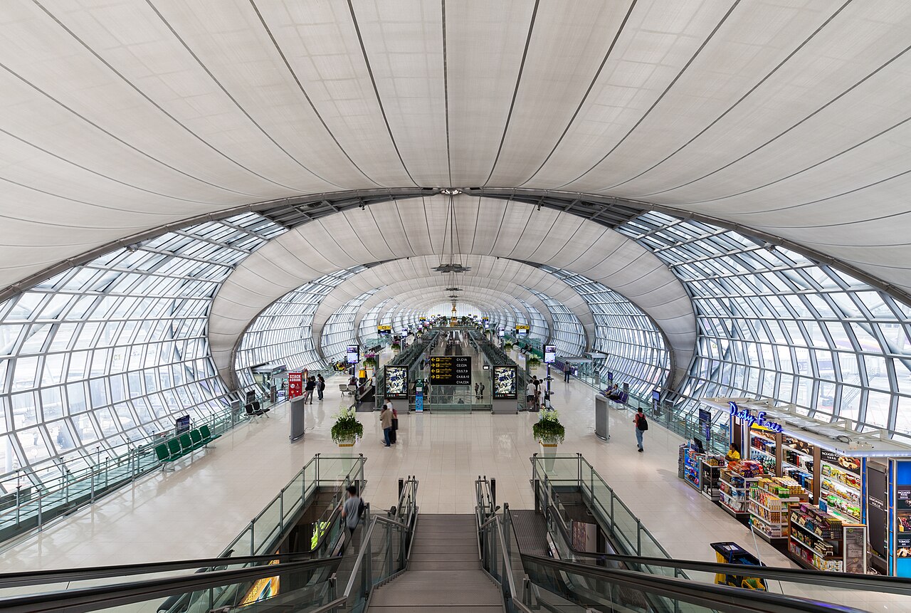 Interior luminoso del aeropuerto Suvarnabhumi de Bangkok, con grandes ventanales y viajeros.